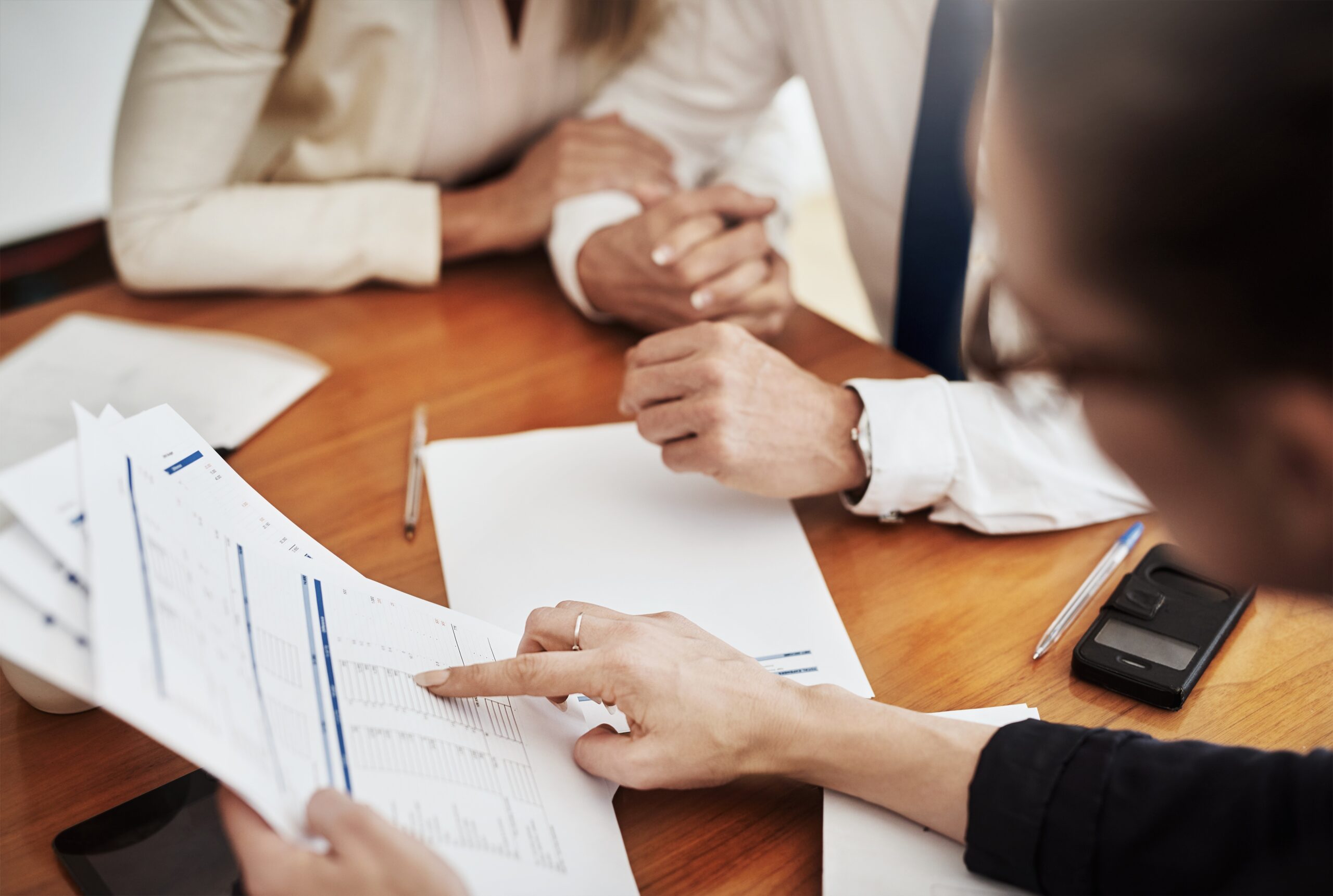 Business professionals reviewing documents and performance data during an ESG reporting and governance evaluation meeting.